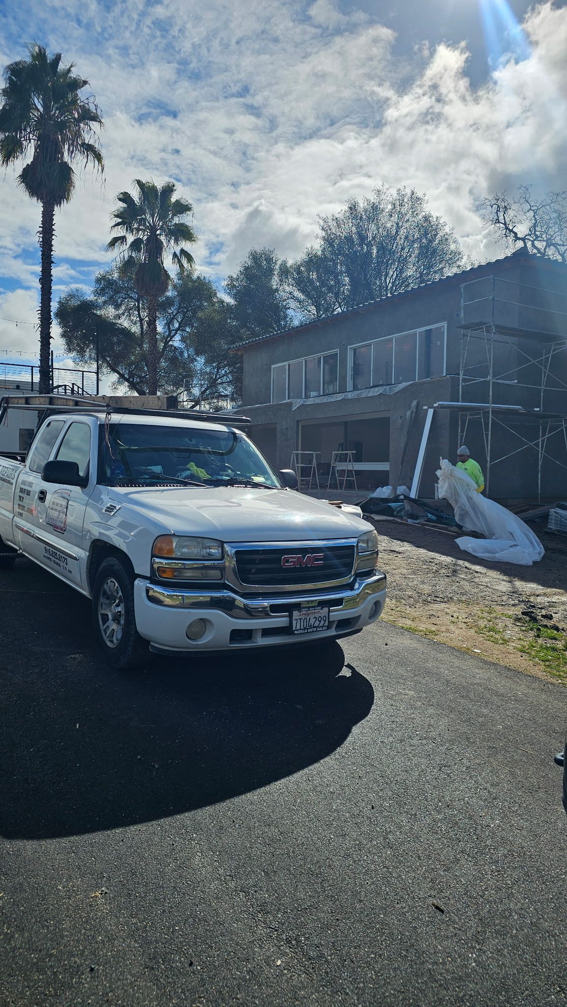 A white truck is parked in front of a building under construction.
