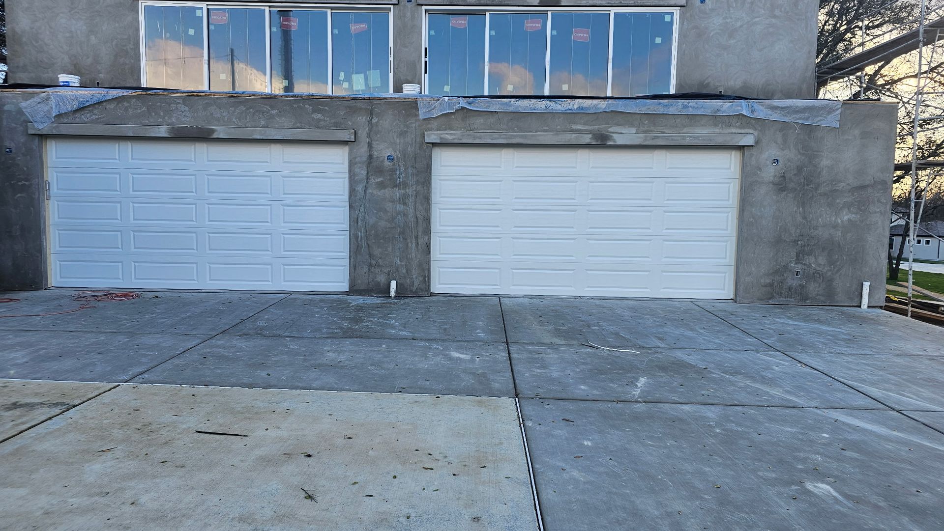 A building with two garage doors and a concrete driveway in front of it.