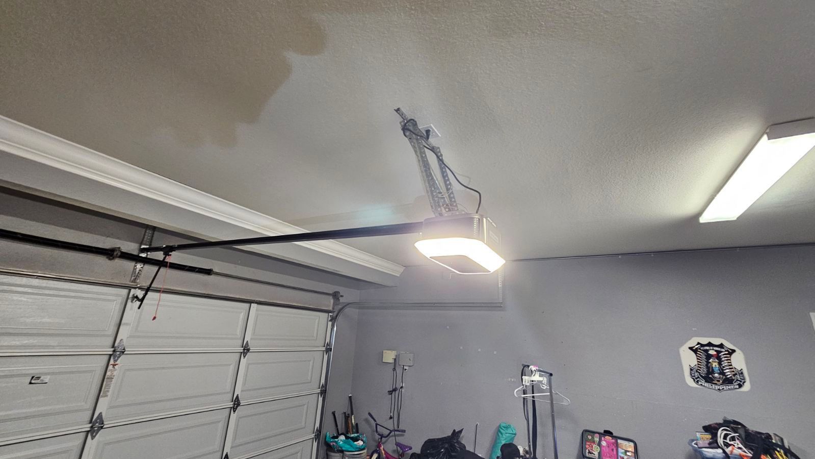 A garage with a garage door open and a light hanging from the ceiling.