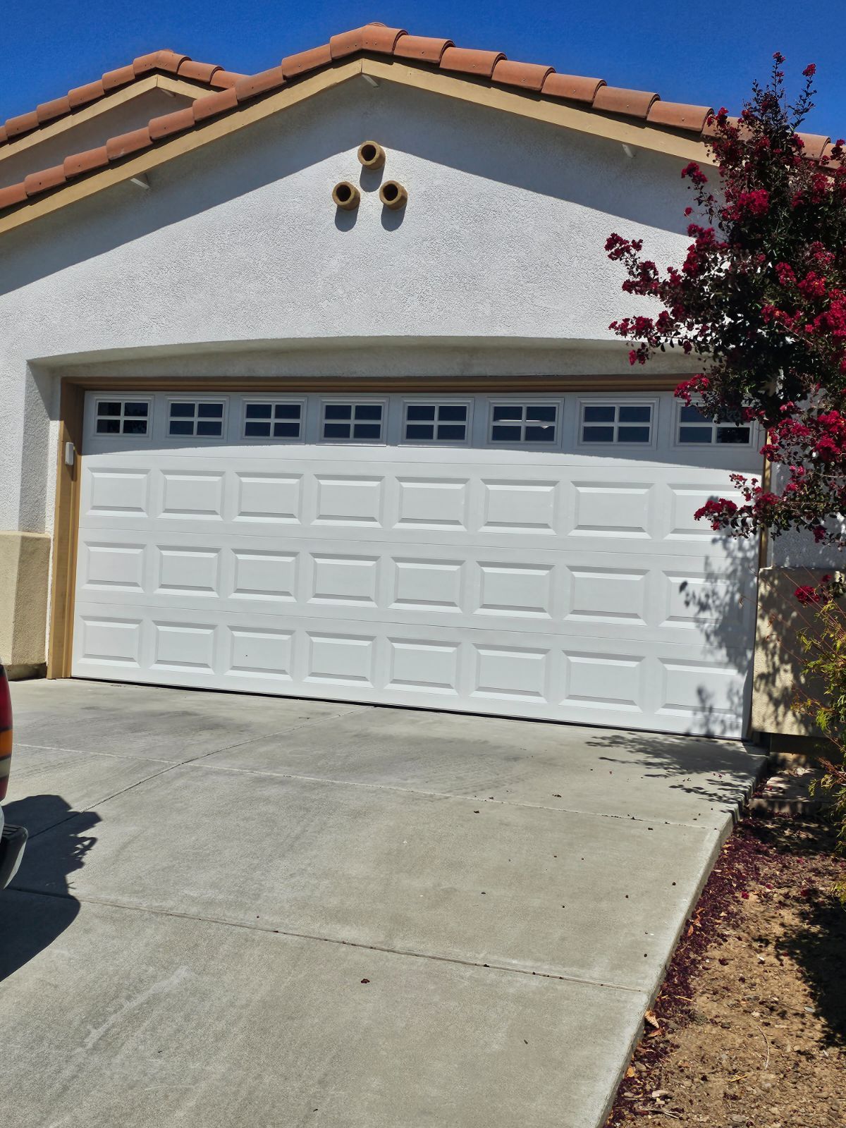 A white truck is parked in front of a white garage door