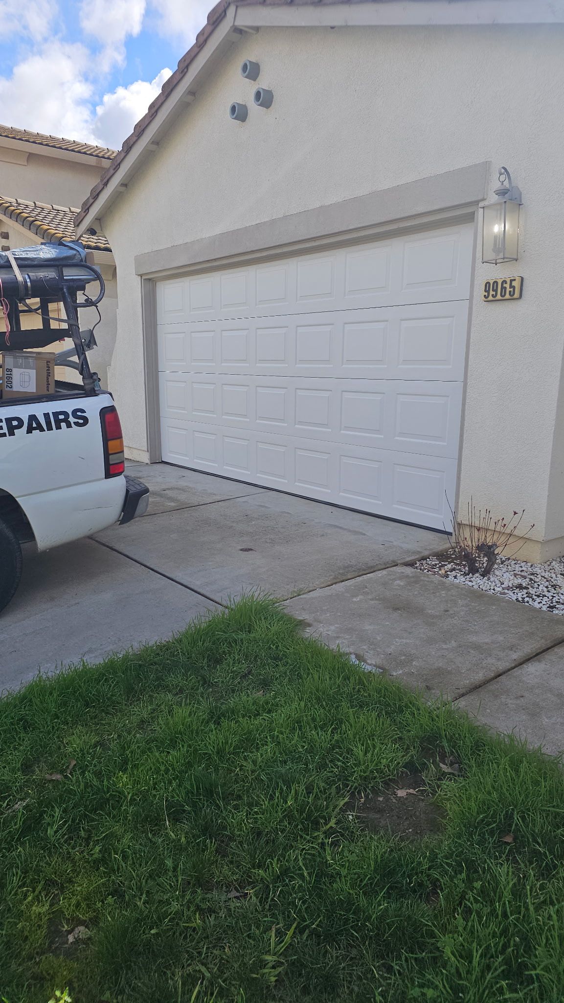 A white truck is parked in front of a garage door.