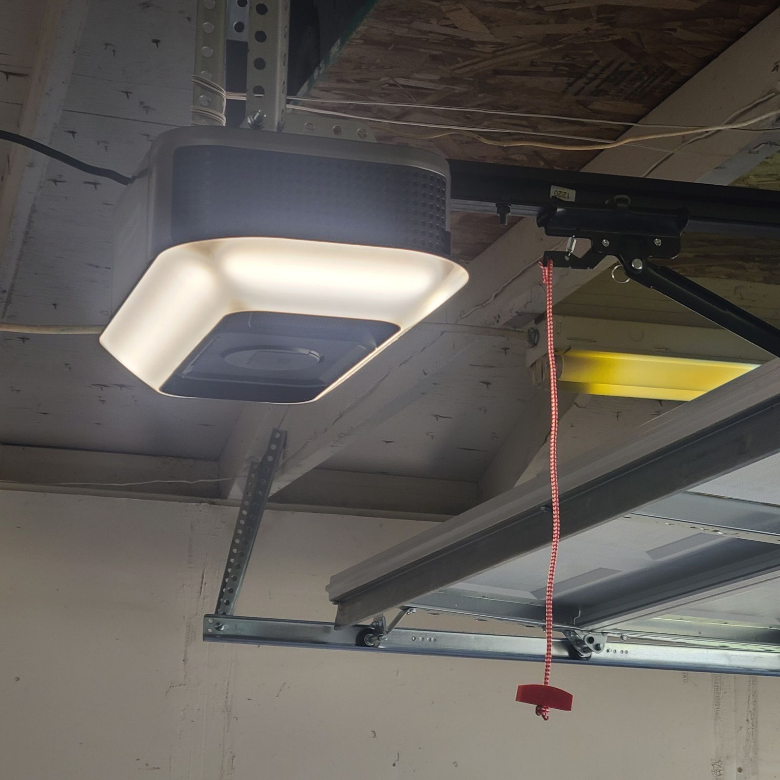 A garage door opener with a light hanging from the ceiling