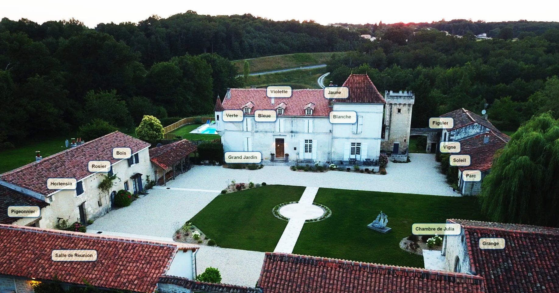 an aerial view of a large white house with red tile roofs