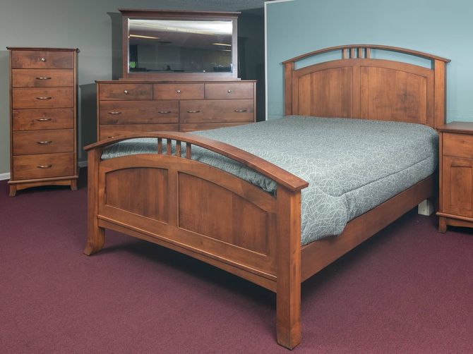 A bedroom with a bed , dresser , nightstand and mirror