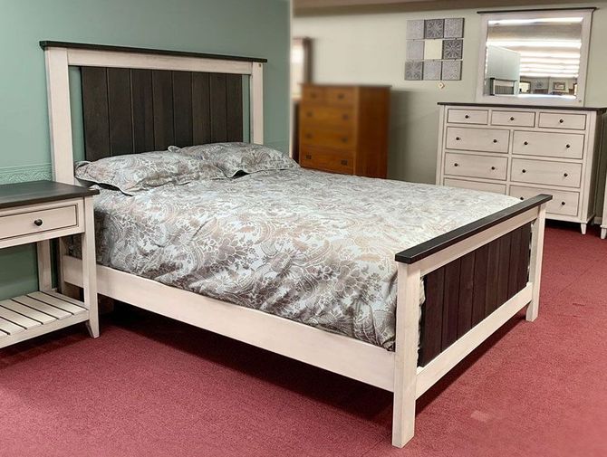 A bedroom with a bed , nightstand , dresser and mirror.