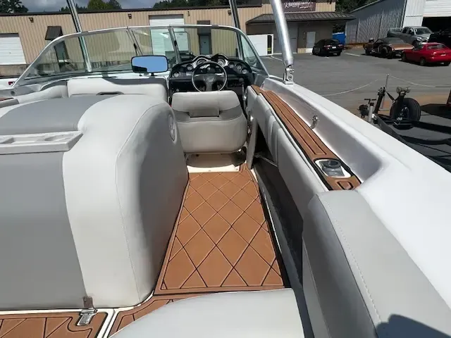 Boat interior with gray and tan seats, brown floor, and steering wheel.