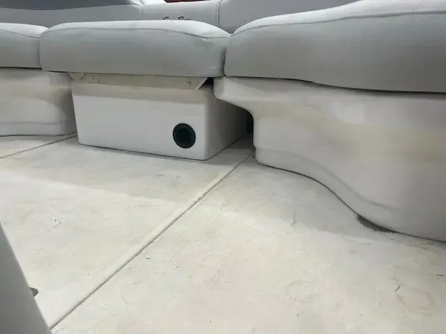 White pontoon boat interior with light gray seating and a black speaker.