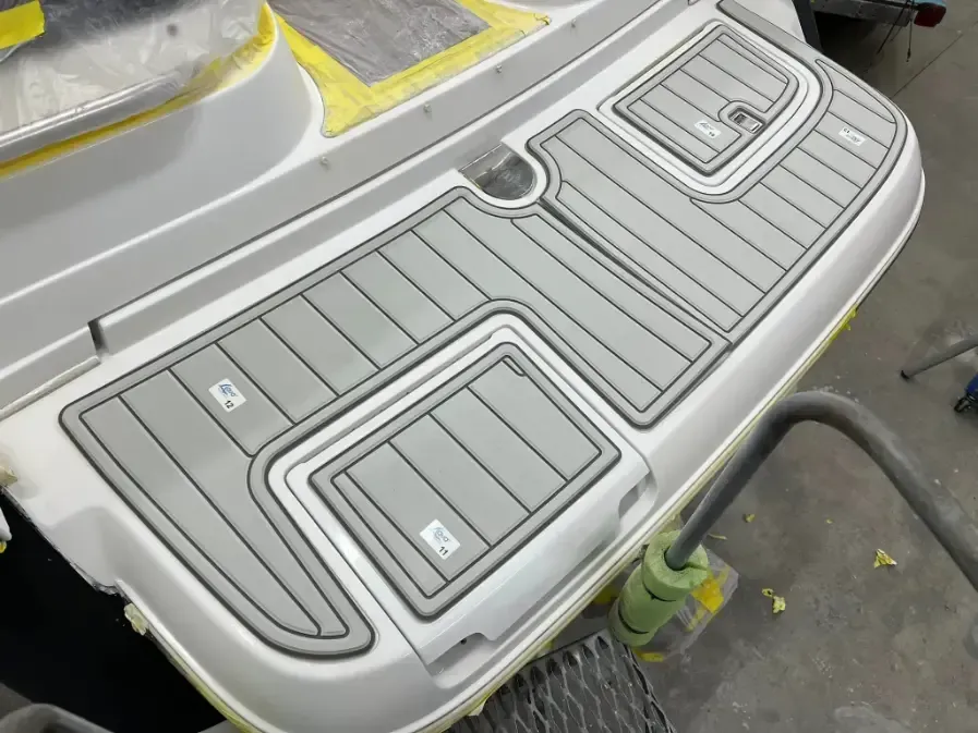 Boat stern with gray non-skid padding and storage compartments.