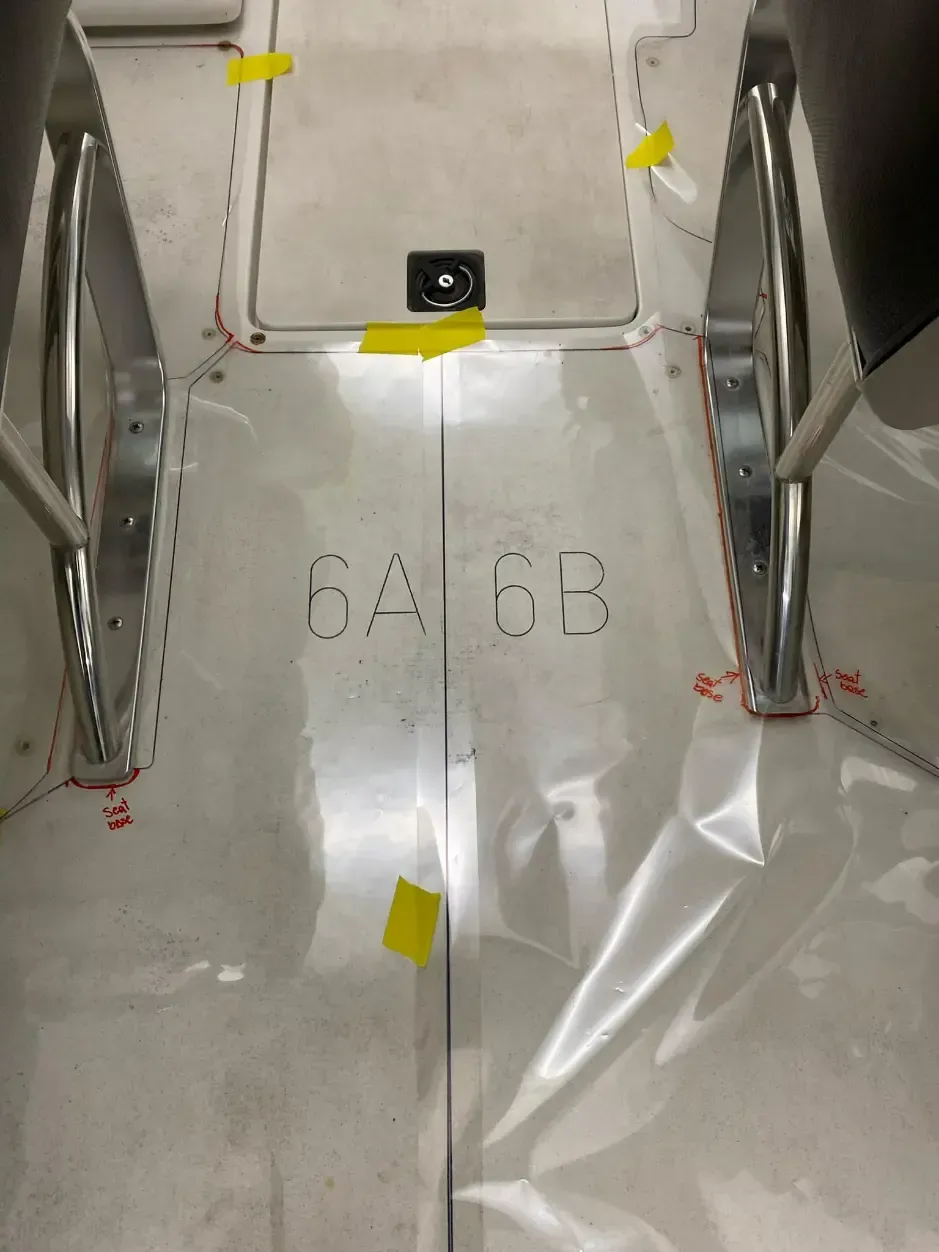 Interior view of an aircraft cabin floor, marked with letters and numbers.