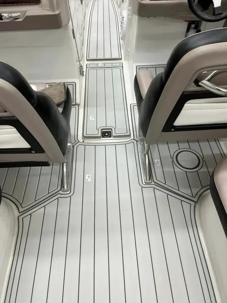 Boat interior with black and white flooring, captain chairs, and console.