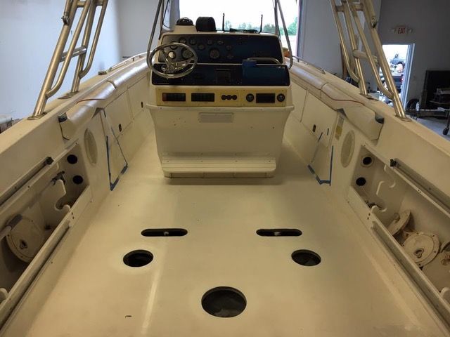 Interior view of a white boat deck with control console and railing.