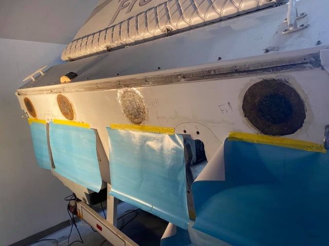 Boat stern with round holes and blue tape.