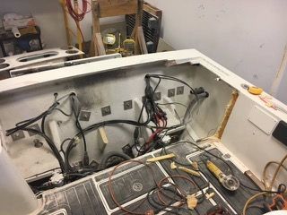 Boat compartment being worked on, showing wiring, tools, and exposed structure. Interior shot.