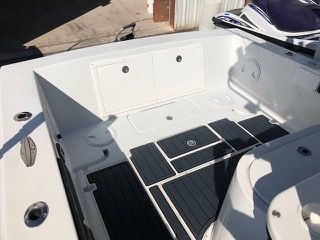Interior of a white boat with black flooring and storage compartments.