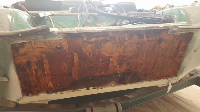 Boat hull side with exposed, damaged wood.