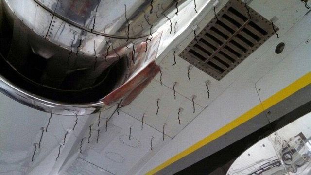 Interior aircraft view, showing vent, metal fixtures, and exposed wires.