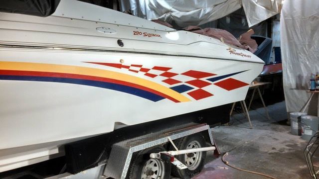 White speedboat on a trailer with colorful checkered and rainbow decals.