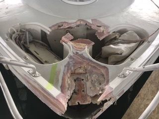 Damaged boat bow with exposed interior, showing torn fiberglass and structural damage.