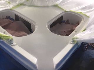 White boat interior with two storage compartments, masked for painting.