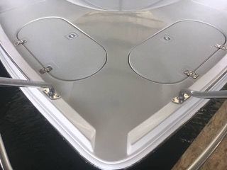 Boat bow with two oval hatches and a stainless steel railing.