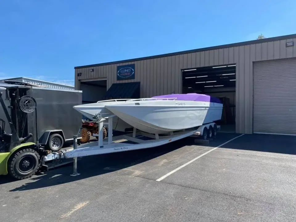 White yacht on supports at a marina under a clear blue sky.