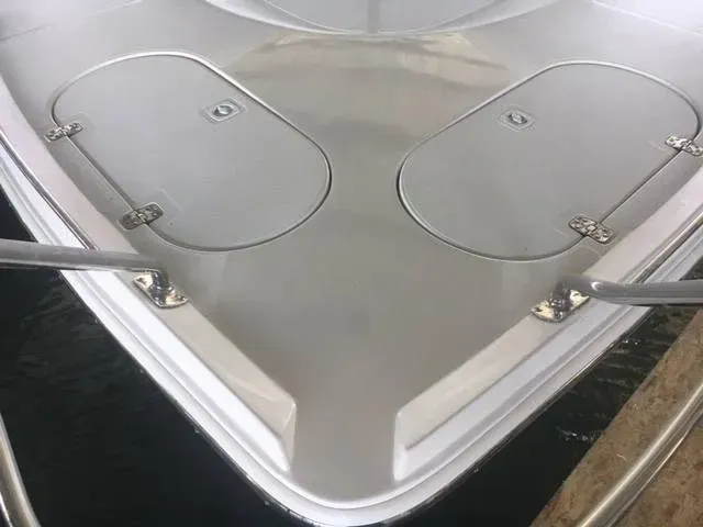 Bow of a white boat with two storage hatches and metal railings.