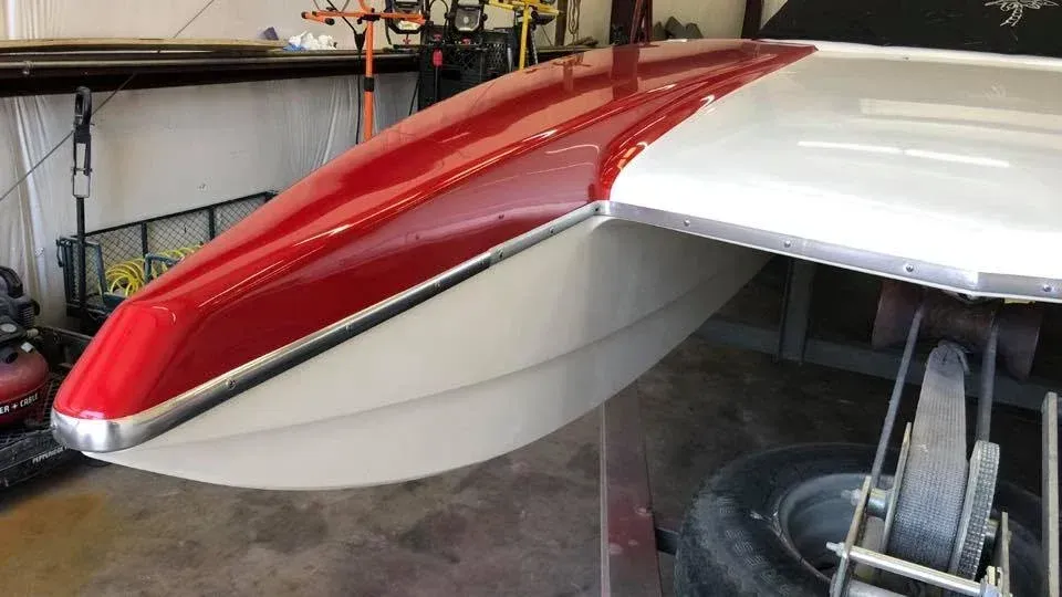 Red and white airplane wing with silver trim, in a garage setting.