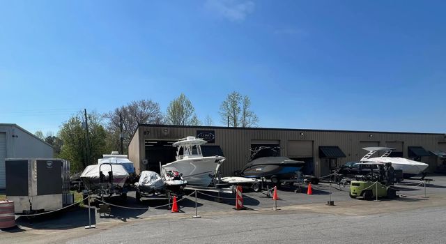 Boats on trailers outside a building, sunny day.