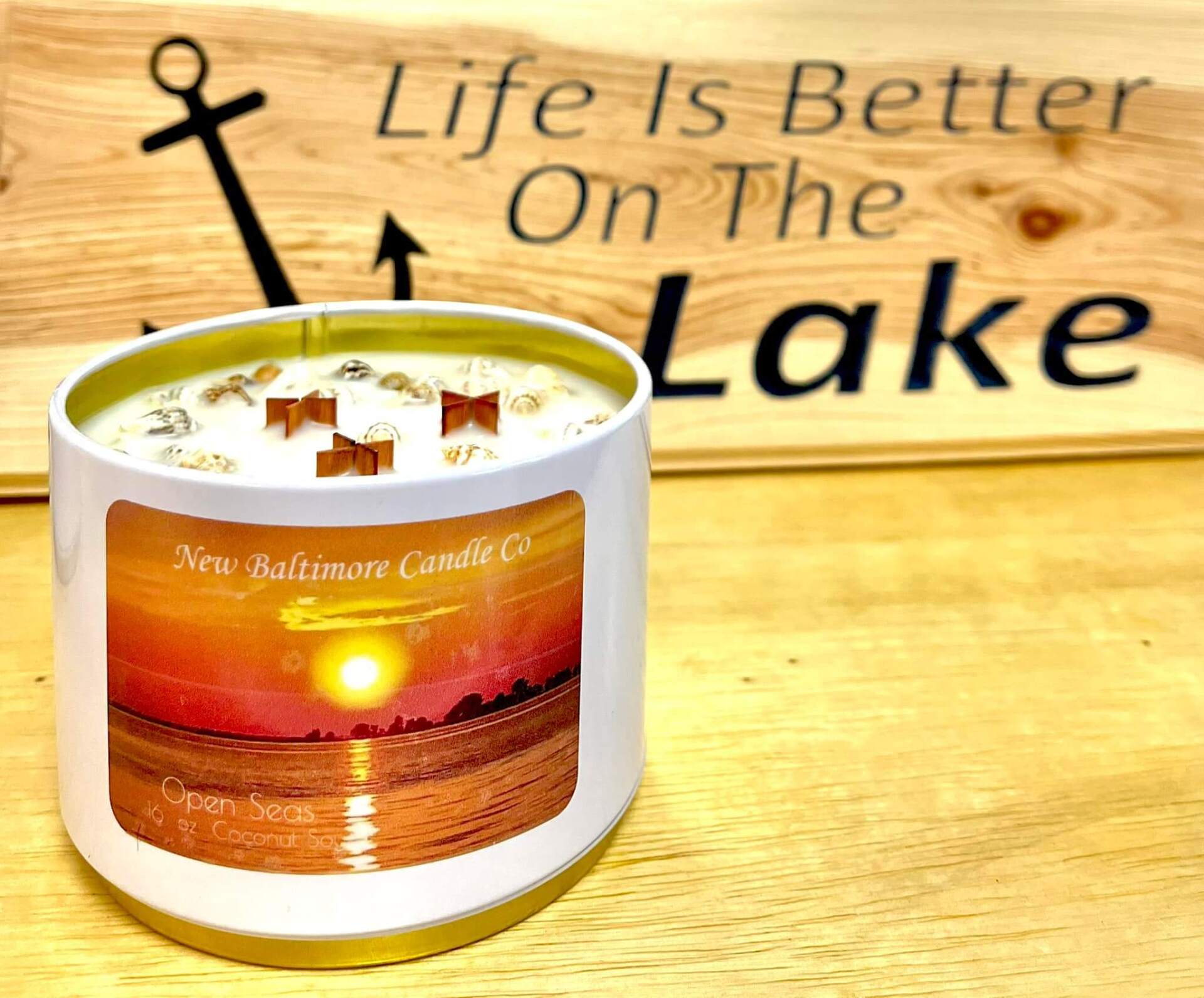 A candle in front of a sign that says life is better on the lake