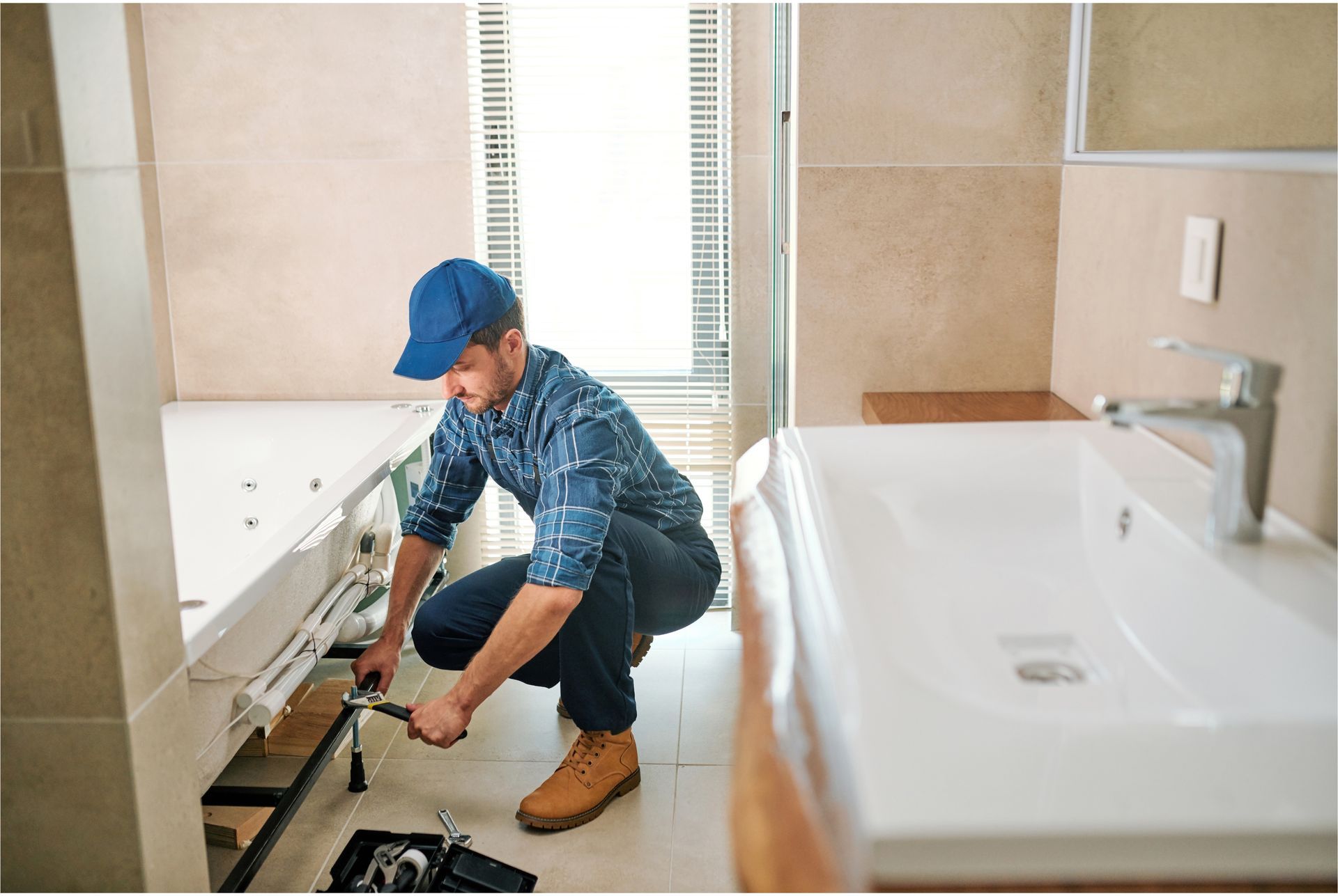 A plumber is working on a bathtub in a bathroom.