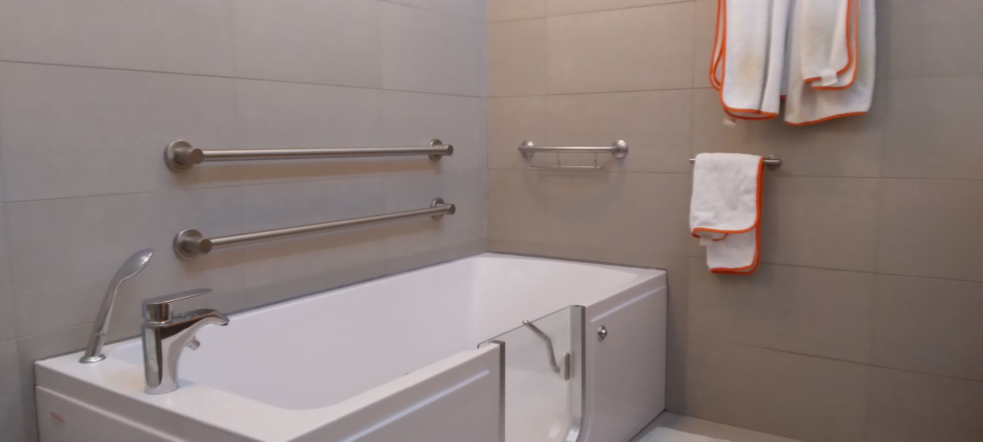 A bathroom with a bathtub and towels hanging on the wall.