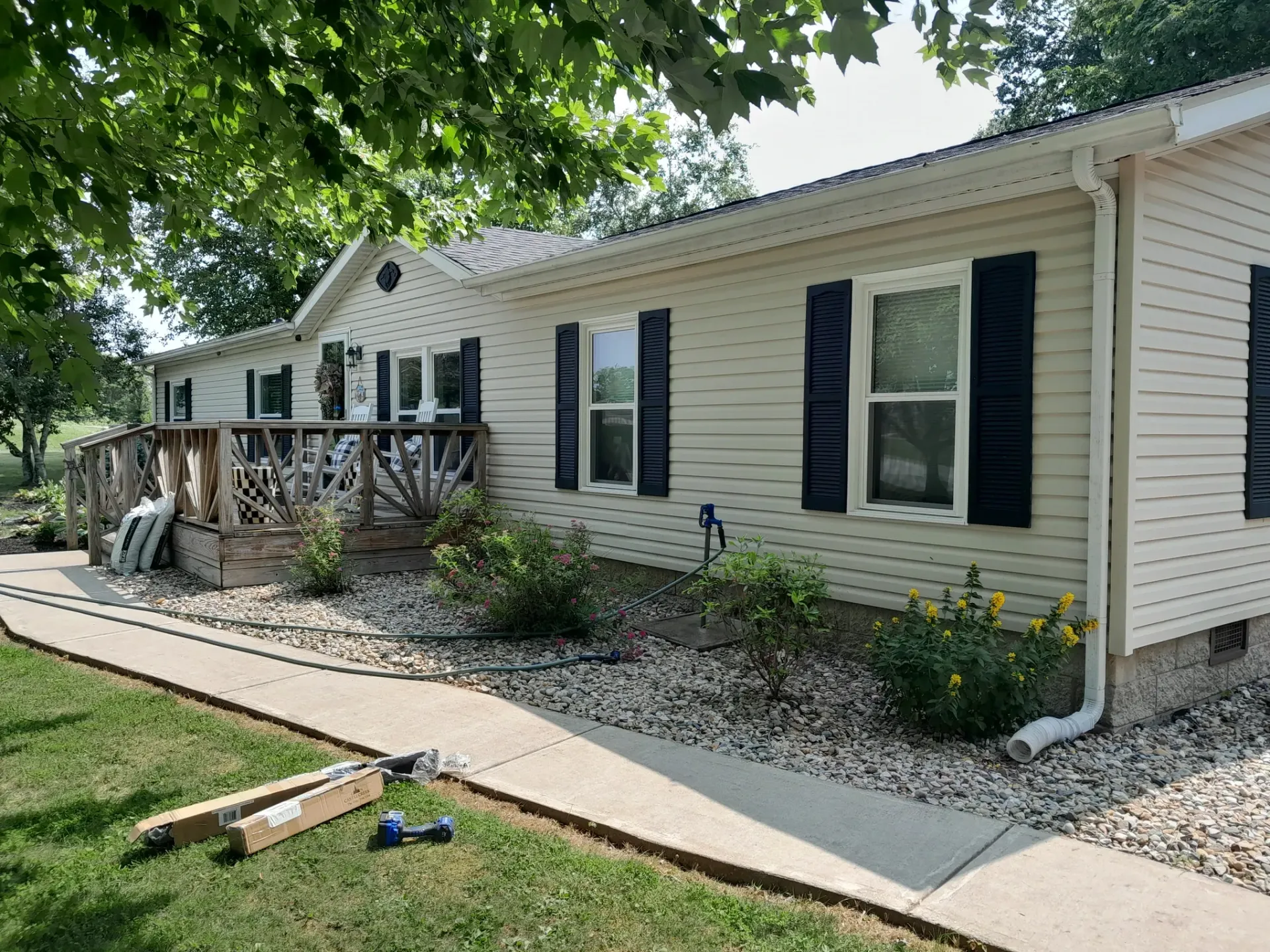 A white mobile home with black shutters and a walkway in front of it.
