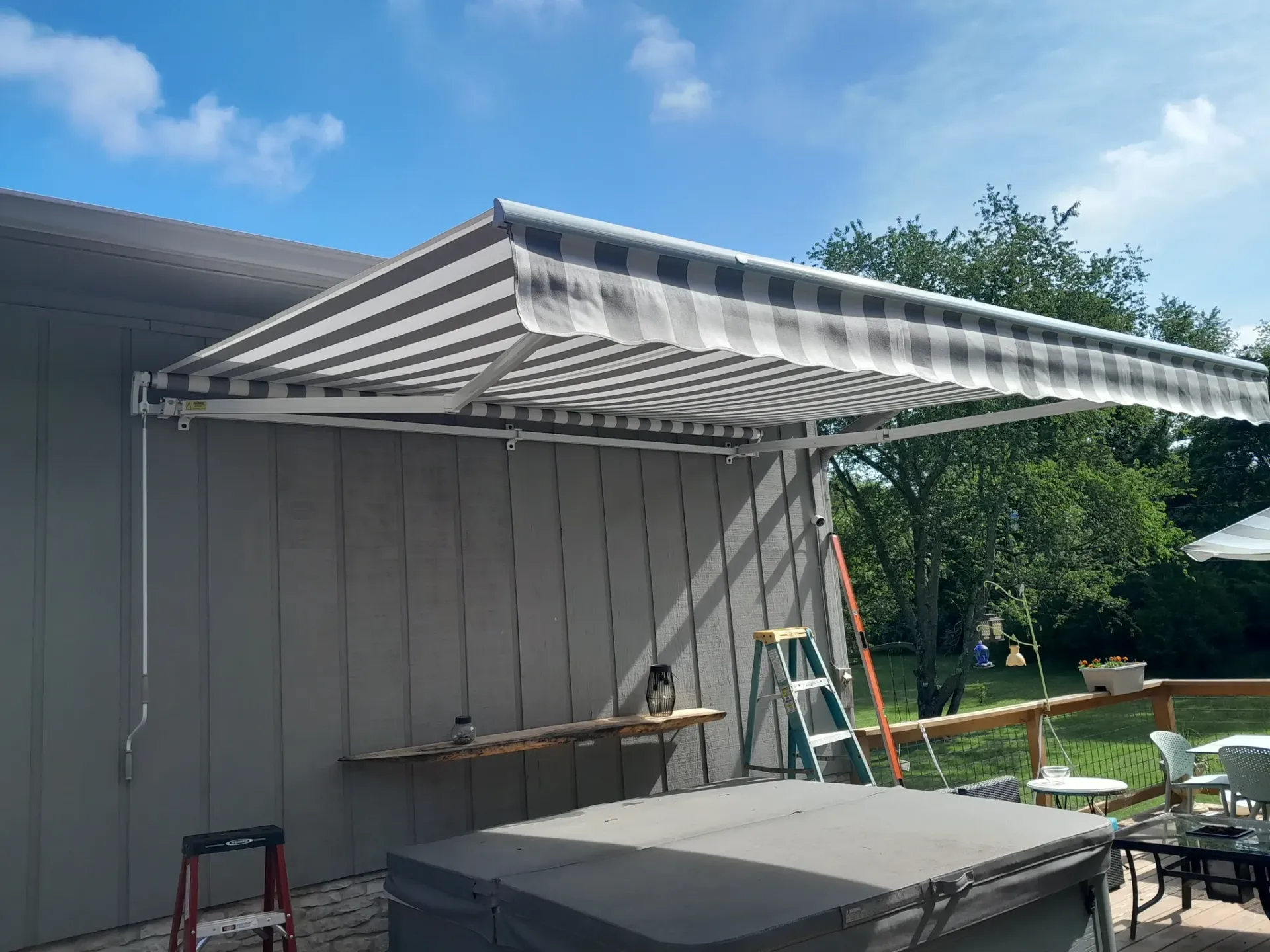 Retractable striped awning installation for outdoor shade and handyman home improvement service