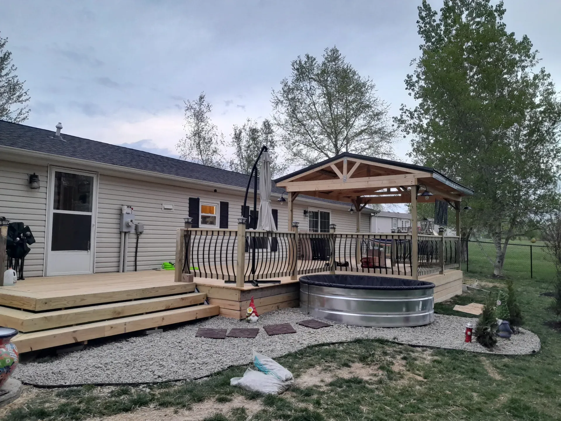 A mobile home with a large deck and gazebo in the backyard.