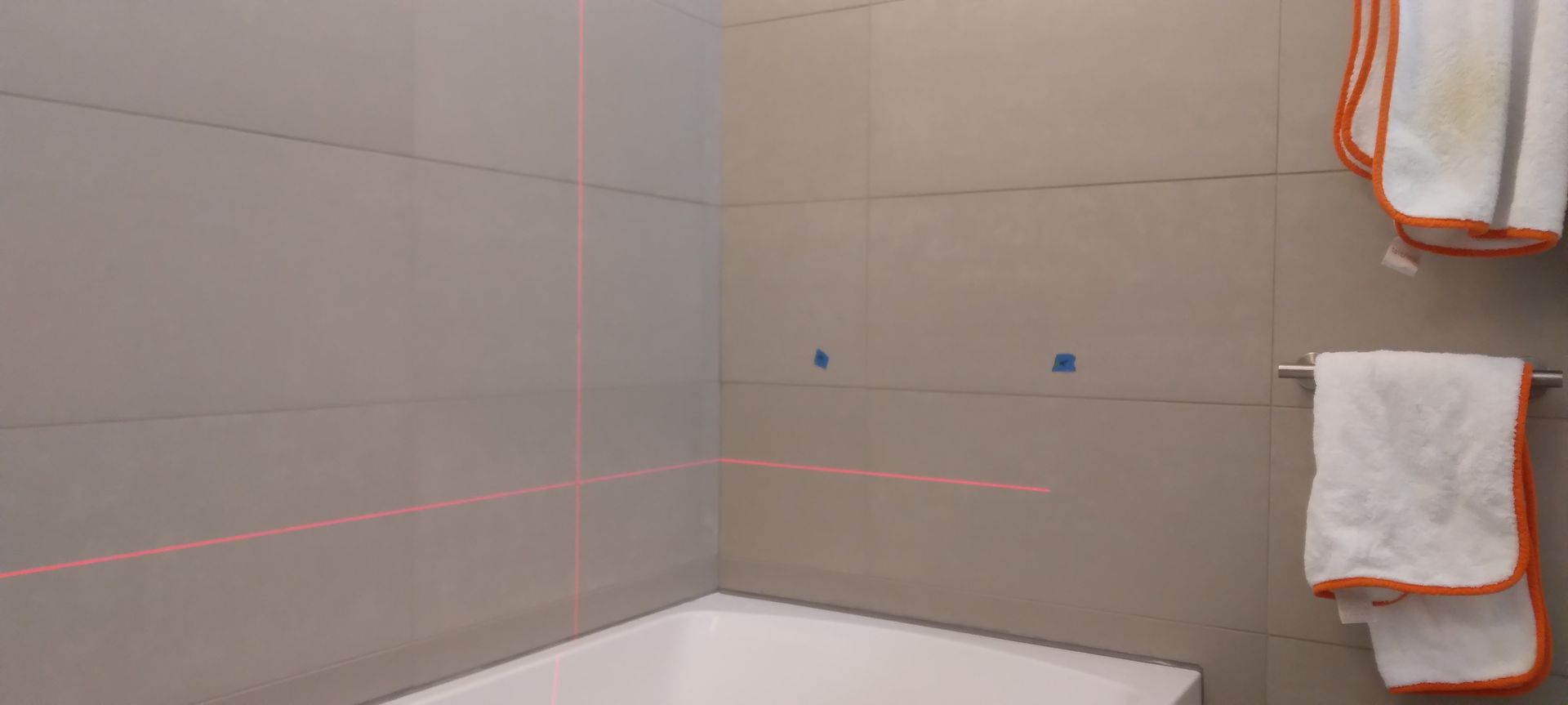 Bathroom remodel with wall tile installation using laser level for precise alignment