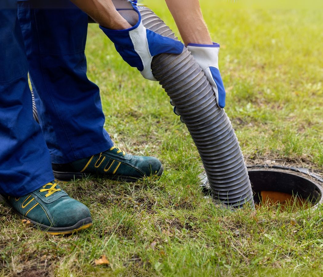 A person is pumping a hose into a manhole cover.
