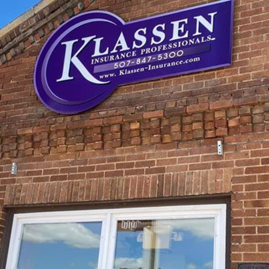 Ryan J. Bourlier, CPA in Kimball, NE Klassen Insurance Professionals sign on a brick building with a white-trimmed window. Purple and white color scheme.