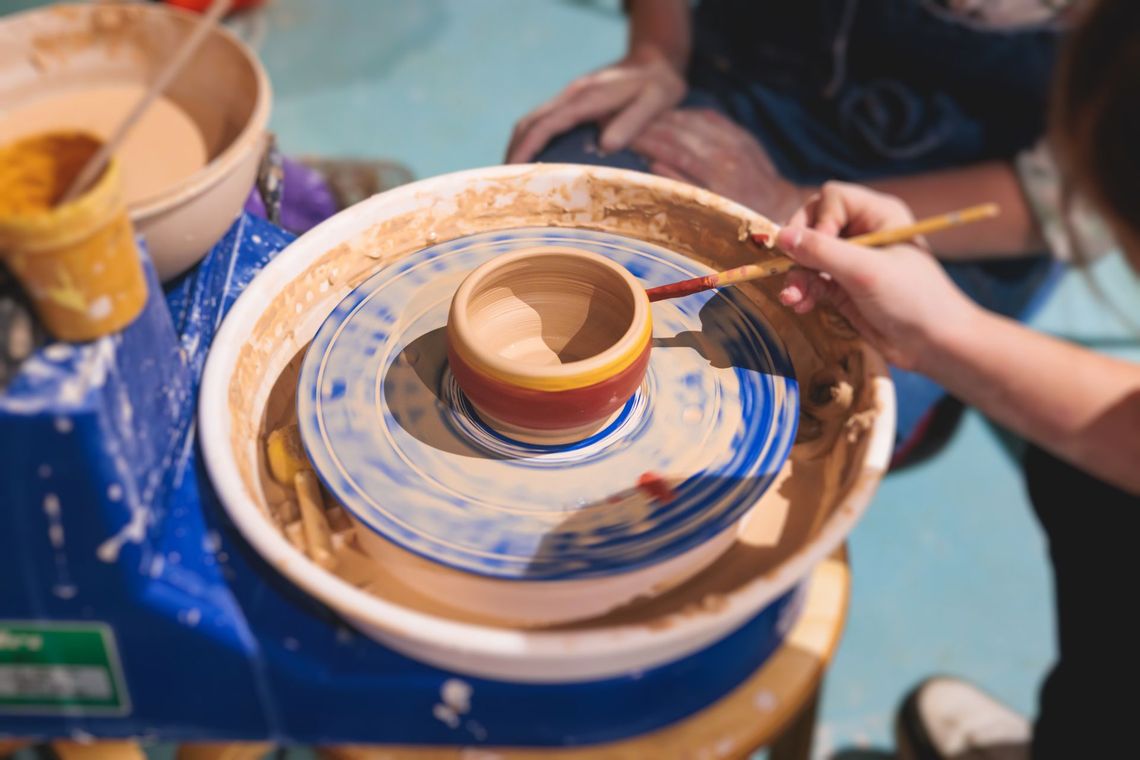 A person is painting a bowl on a pottery wheel.