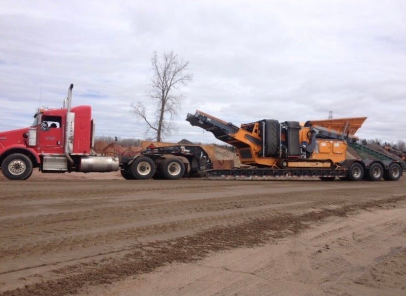 Vue intérieure d'une longue pièce où l'on pose un parquet. Une personne travaille au fond de la pièce.