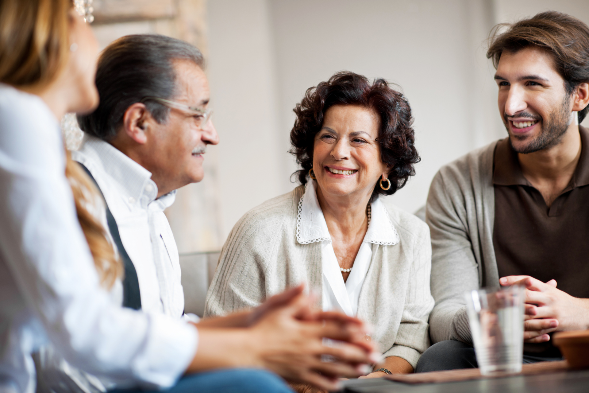 Family of four smiling and chatting in a living room.