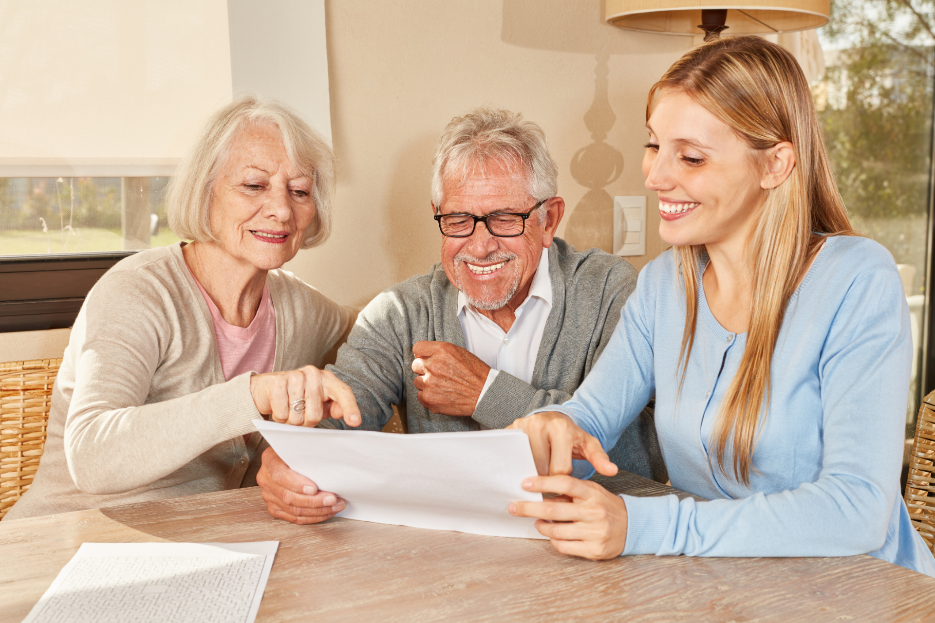 Senior couple and young woman reviewing papers together at a table; all are smiling.