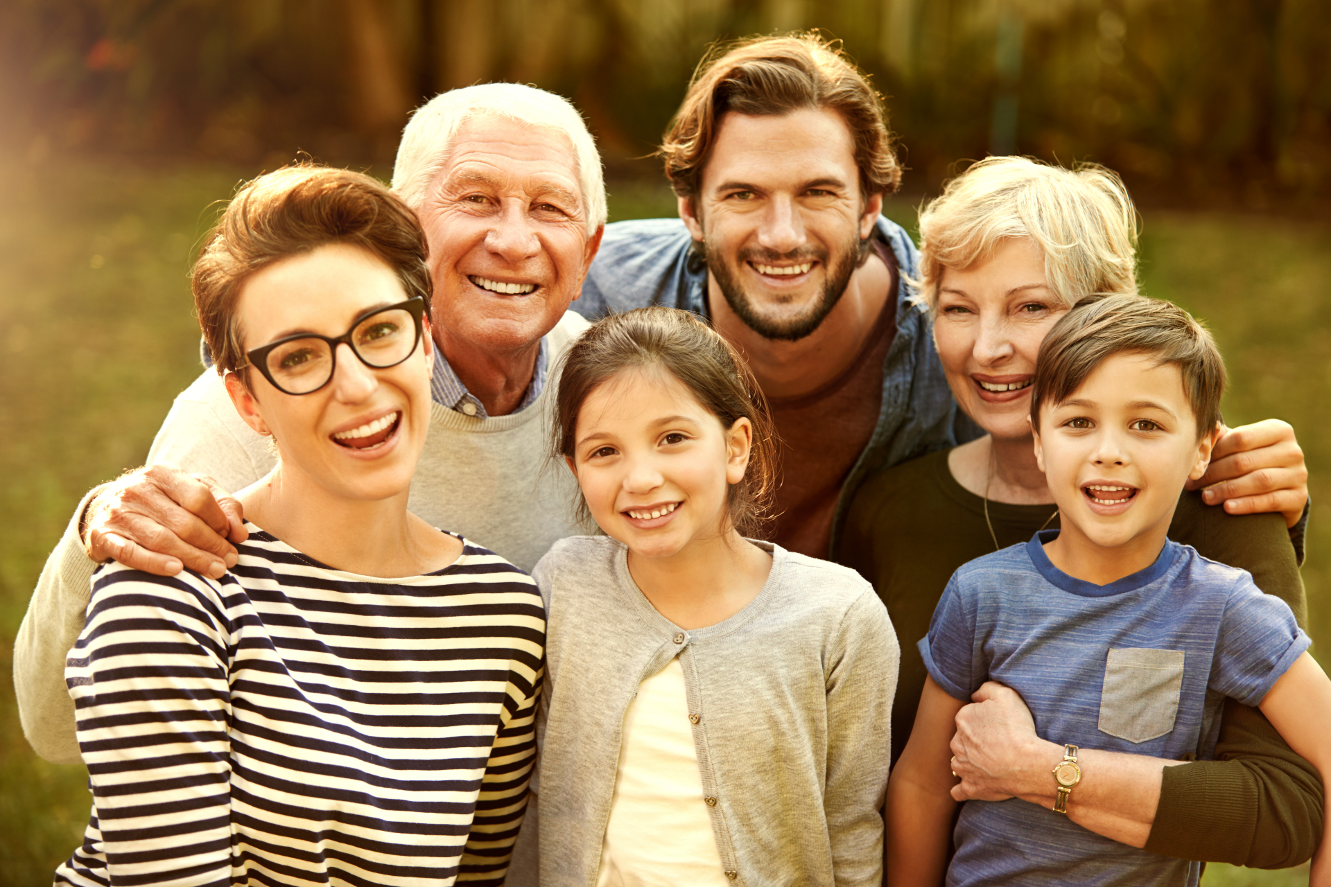 Multi-generational family smiling together outdoors.