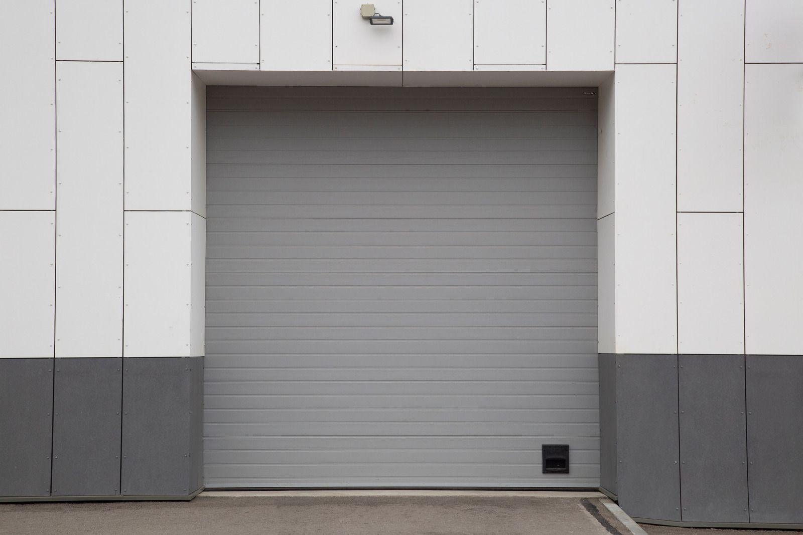 A gray garage door is open on the side of a building.