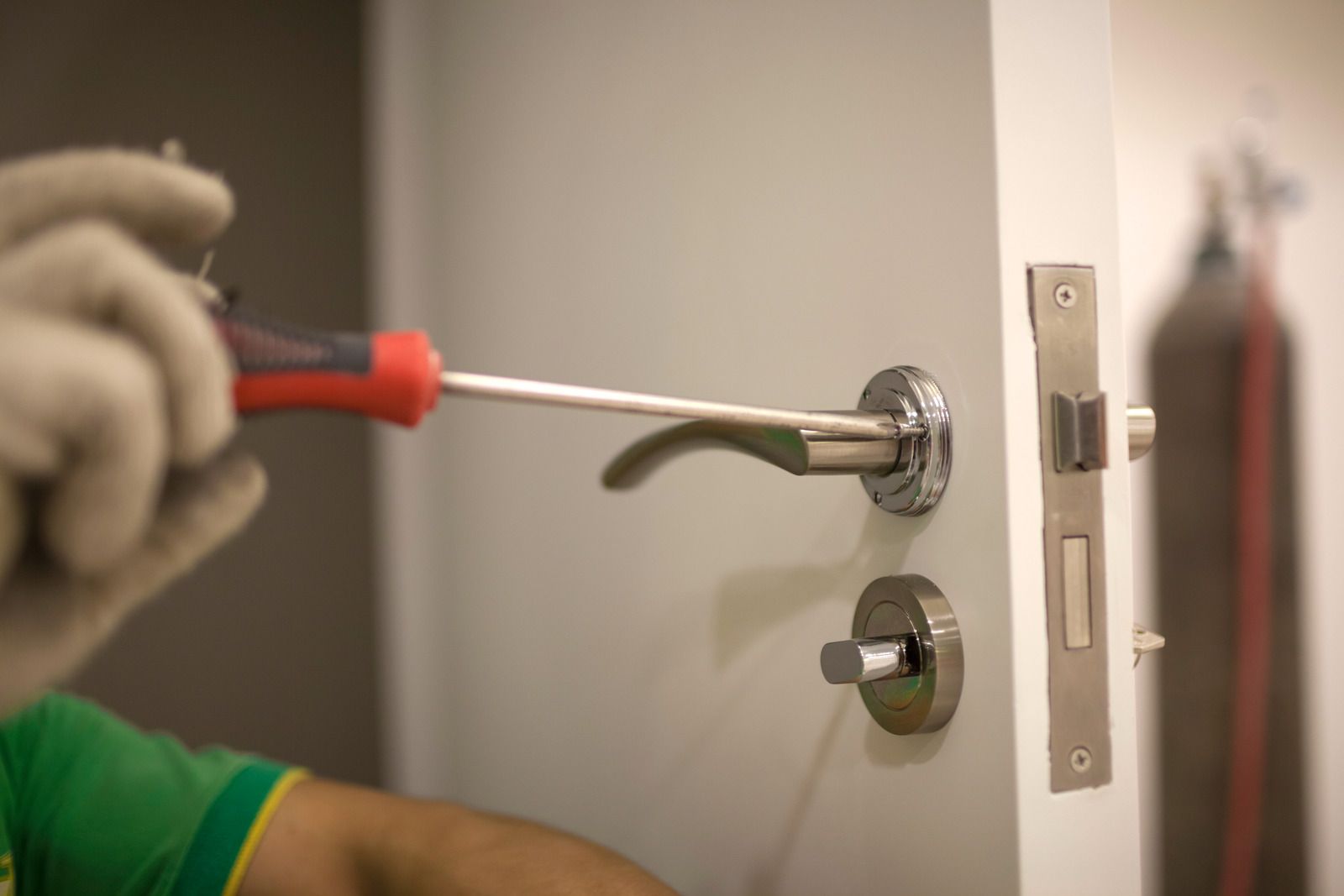 A man is fixing a door handle with a screwdriver.