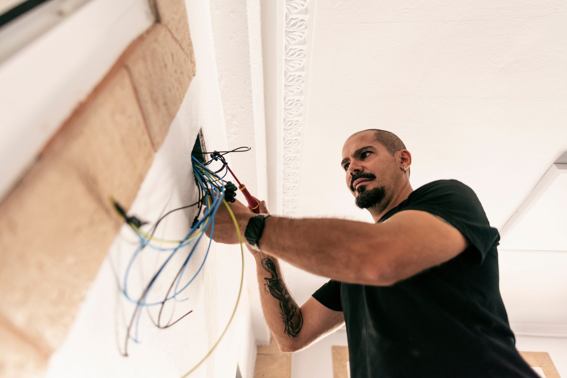 A man is working on a wall with wires.