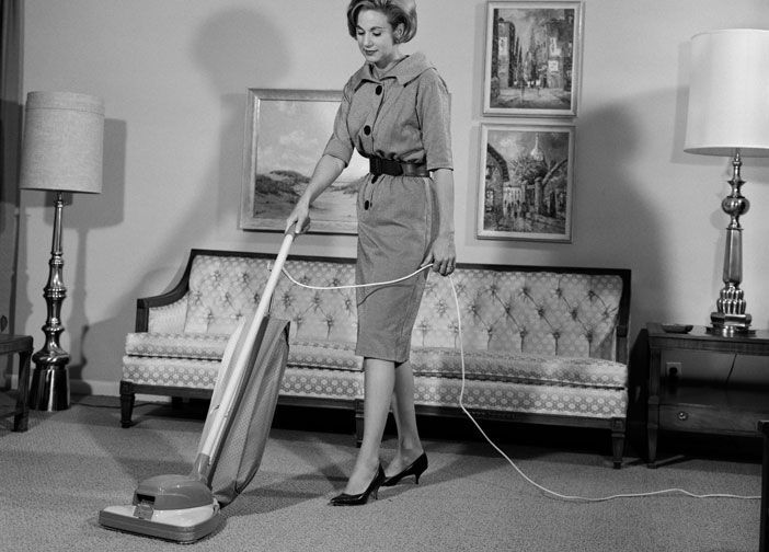 A woman is using a vacuum cleaner in a living room.