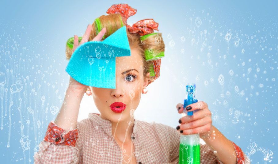 A woman with curlers in her hair is holding a spray bottle and a sponge in front of her face.