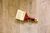 A paint brush with a red handle is laying on a wooden surface.