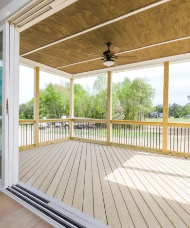 An empty deck with a ceiling fan and sliding glass doors