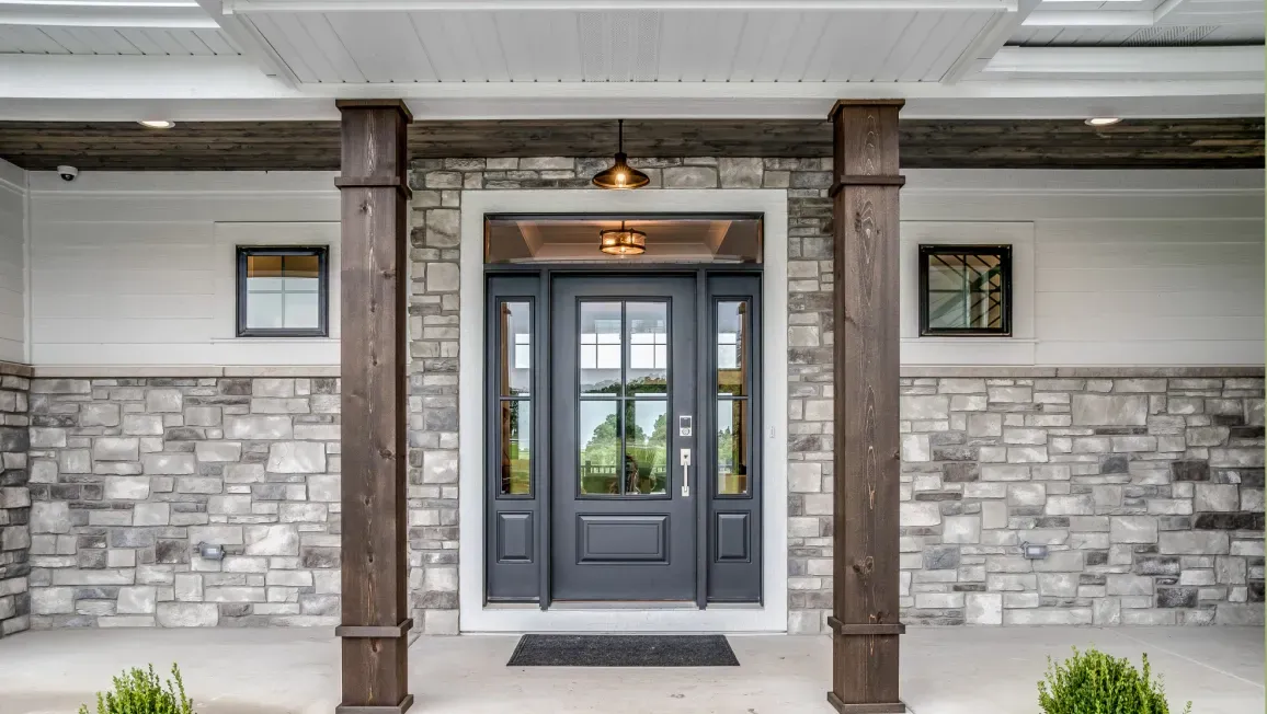 The front door of a house with a stone wall and a black door.